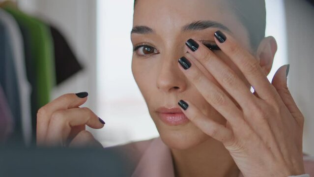 Serious lady putting false eyelashes home closeup. Blogger making makeup talking