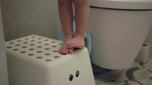 barefoot child legs standing step stool footstool in bathroom. tiptoes tiny toes step move while baby washing. feet movements pure innocent baby toes on step stool. climb toddler bare legs