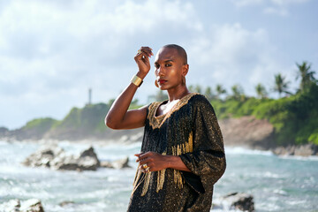 Androgenous black fashion model stands on scenic tropical beach portrait. Non-binary ethnic person...