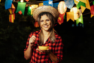 Woman eating Canjica, a traditional corn-based dessert, at the Festa Junina (June Festival)...