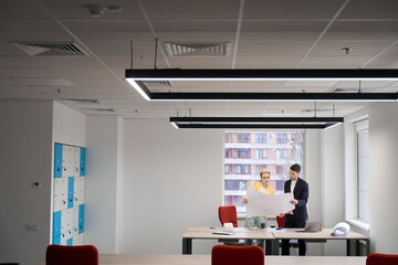 Designers considering plan of house in the office