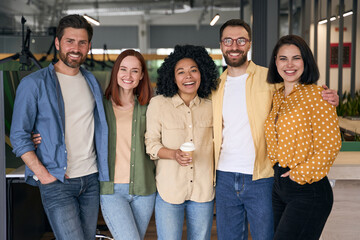Group of happy multiracial business people, colleagues coworkers standing together in modern office. Portrait smiling stylish friends wearing casual clothes looking at camera. Diversity concept - obrazy, fototapety, plakaty
