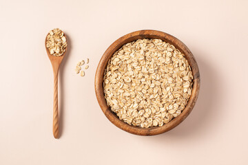 raw oatmeal in a wooden bowl, wooden spoon, light background.