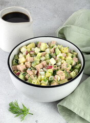 Okroshka - russian cold soup with vegetables, sausage, herbs, kvass and black bread on a gray background.