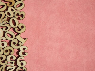 wooden numbers are randomly arranged on pink suede