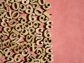 wooden numbers are randomly arranged on pink suede