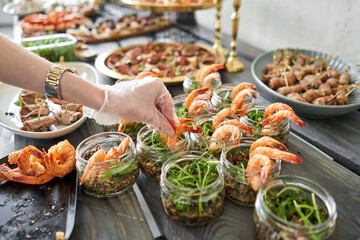 The waiter sets the table. Delicious fresh seafood, shrimp with fresh vegetables. buffet table with lots of delicious snacks.