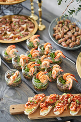 Delicious fresh seafood, shrimp with fresh vegetables. buffet table with lots of delicious snacks. canapes, bruschetta, and little desserts on wooden plate board