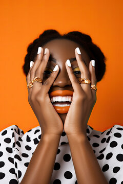 Generative AI illustration of portrait of shy black female fashion model covering face with hands with rings and smiling against orange background