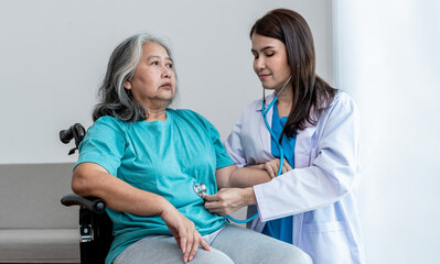 an Asian doctor woman Using a stethoscope Listen to abdomen of elderly woman patients. to annual health check of the elderly and health care concept.