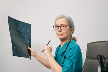 Elderly medical worker holds an MRI scan of the brain in her hands