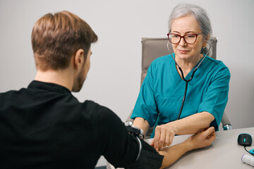 Obraz premium Attentive female therapist measures blood pressure to a young patient