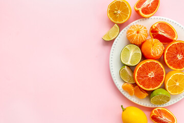 White plate full of fresh citrus fruits, top view