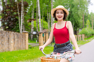 Naklejka na ściany i meble Portrait beautiful young girl in hat with bicycle on street in countryside
