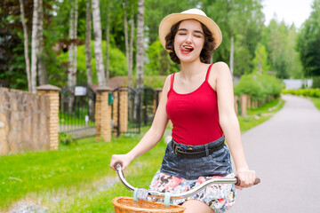 Portrait beautiful young girl in hat with bicycle on street in countryside