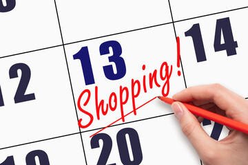 13th day of the month. Hand writing text SHOPPING and drawing a line on calendar date.