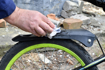 A cyclist washes a bicycle fender with a napkin.