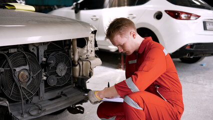 mechanic is checking front car, which enters garage in wrecked state, mechanic checks condition,...