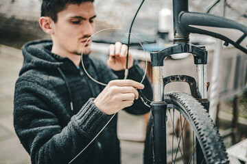 A young man pulls a brake cable on the handlebars of a bicycle.