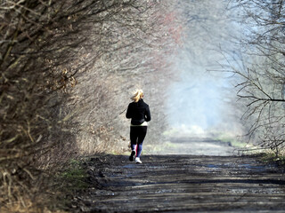 Młoda wysportowana dziewczyna biegnie lesną drogą