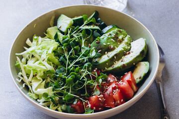 Summer green healthy salad with avocado, arugula microgreens, cucumber, cabbage and tomatoes