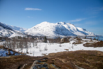 Snowy Hill besides a costal town by a fjord. 
