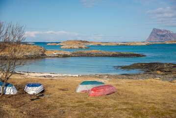 Norwegian coastal bay with small islands and over turned boats on the shore.