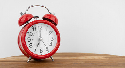 Red alarm clock on grey wall background