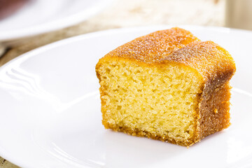 small slice of cornmeal cake, typical Brazilian rural cake made with corn flour, with hot coffee in the background, guava jam in the background with cheese