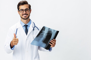 Man doctor in white coat and eyeglasses and stethoscope with a smile looks at patient X-ray images...
