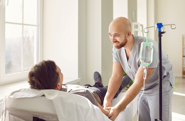 Friendly hospital staff gives intravenous vitamin course infusion to patient. Smiling nurse...