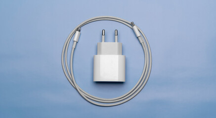 Mobile phone charger with cable wrapped next to it on blue background
