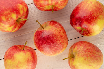 Several organic red apples on a wooden table, macro, top view.
