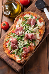 Tipica pinsa romana condita con prosciutto crudo, rucola e parmigiano, cibo italiano 