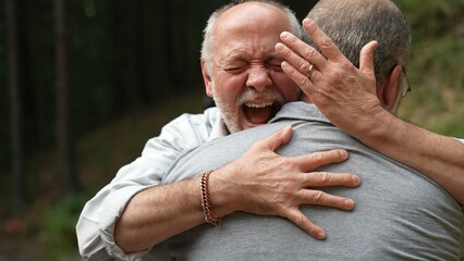 Two gay men hugging with smiles and happiness showing engagement ring for marriage proposal.