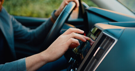 Unknown young man hand which typing needed coordinates on navigator touchscreen inside his modern car close up.
