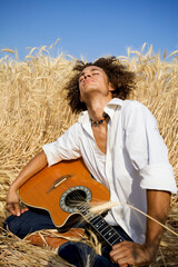 Naklejka na ściany i meble cool guy laying in a cornfield playing guitar