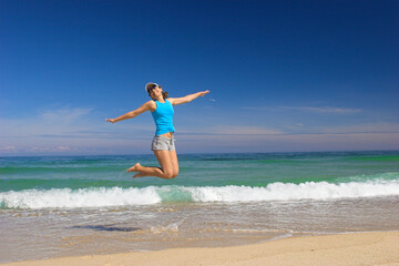 Fototapeta premium Beautiful young woman jumping on a beautiful beach