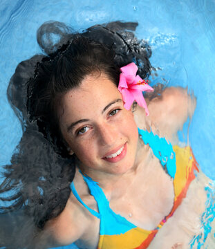 Pretty teen girl with a fower in a pool