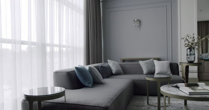 Luxury Modern House Interior With Corner Sofa round table. Minimalist Home Interior. Cozy Modern Furniture Design. Luxury Elegant Room. Modern contemporary Minimalist living room with gray furniture.