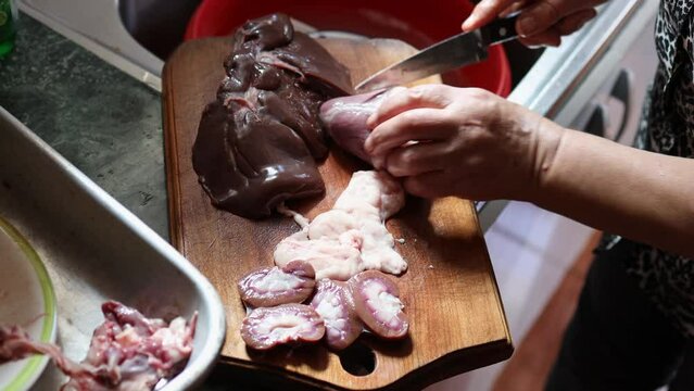 Unrecognizable person hands slicing kidneys, liver and testicles of a lamb, to cook them. Entrails preparation.