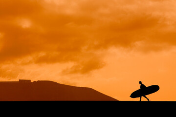 A longboarder silhouetted against the sunset sky