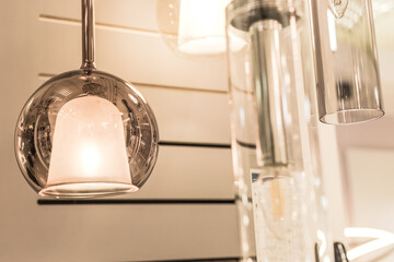 Round glass LED ceiling-mounted chandelier with a decorative element in the shape of a bell inside in the interior