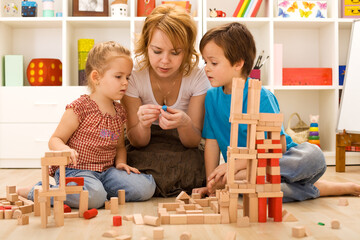 Family activities in the kids room - woman and children sitting on the foor playing