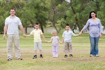 Obraz premium Happy family holding hands on a natural background