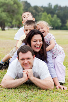 Happy family piled up  on the park and looking at you over natural background