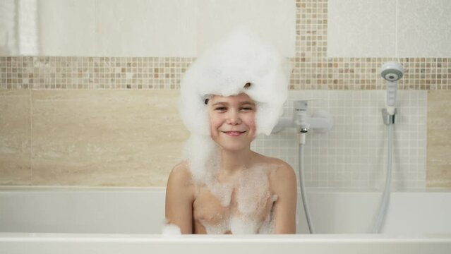 Funny boy with foam on a head dancing in the bath