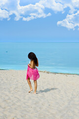 Fototapeta na wymiar lonely girl walking on the beach near the sea with a red pareo