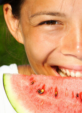 Beautiful woman smiling while eating watermelon outdoors on a hot summerday