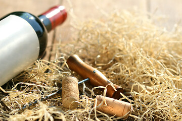 Bottle of red wine with corkscrew and packing straw